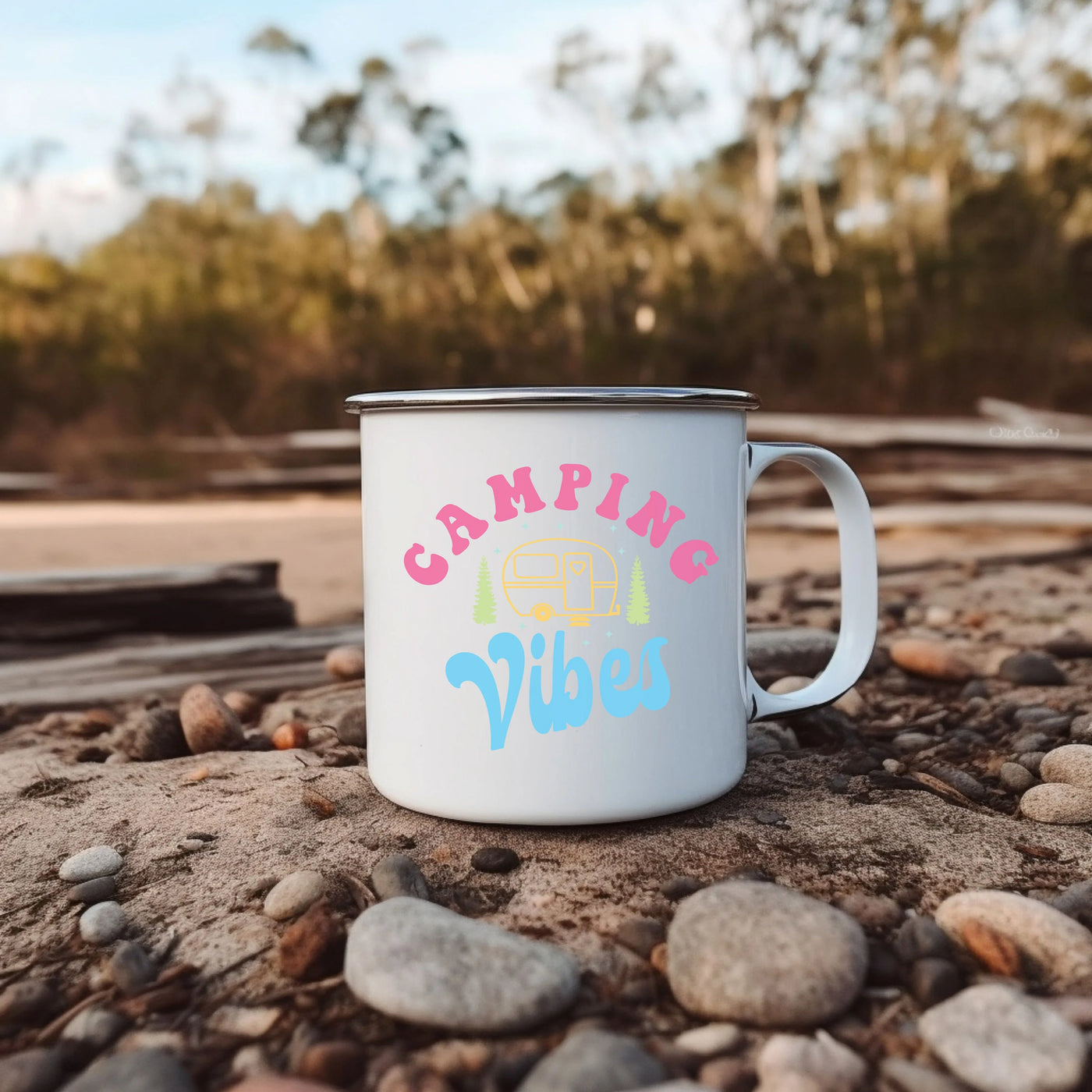 a campfire mug sitting on a rocky beach