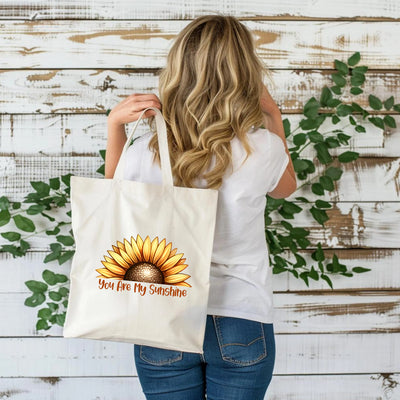 a woman holding a shopping bag that says you are my sunshine