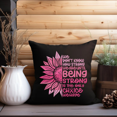 a black pillow with a pink flower on it