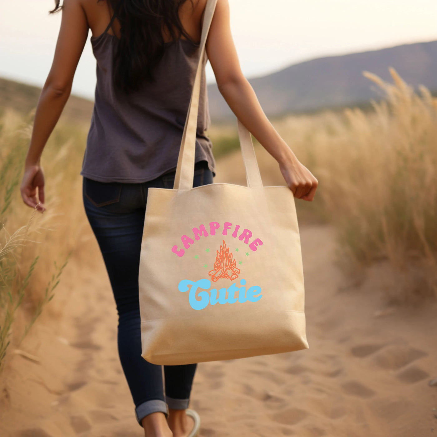 a woman walking down a dirt road carrying a tote bag